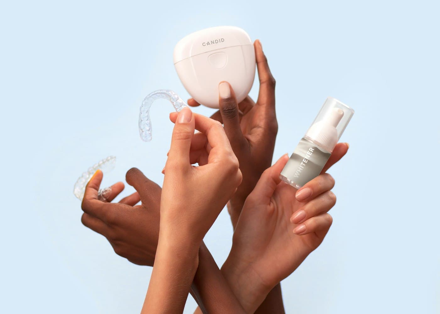 Hands holding clear whitening trays and a whitening gel